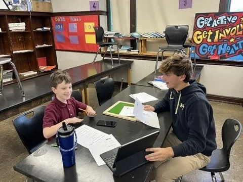 Maclane Zich working one-on-one with a student at a classroom table