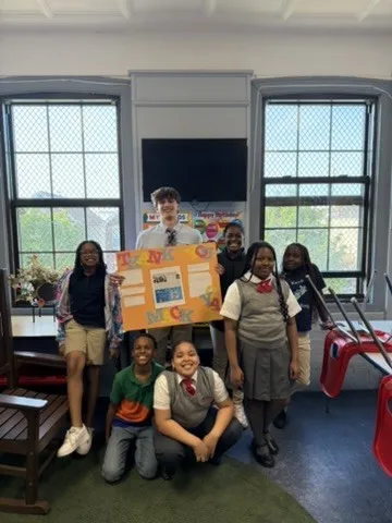 Maclane Zich with a group of students holding their poster in a classroom