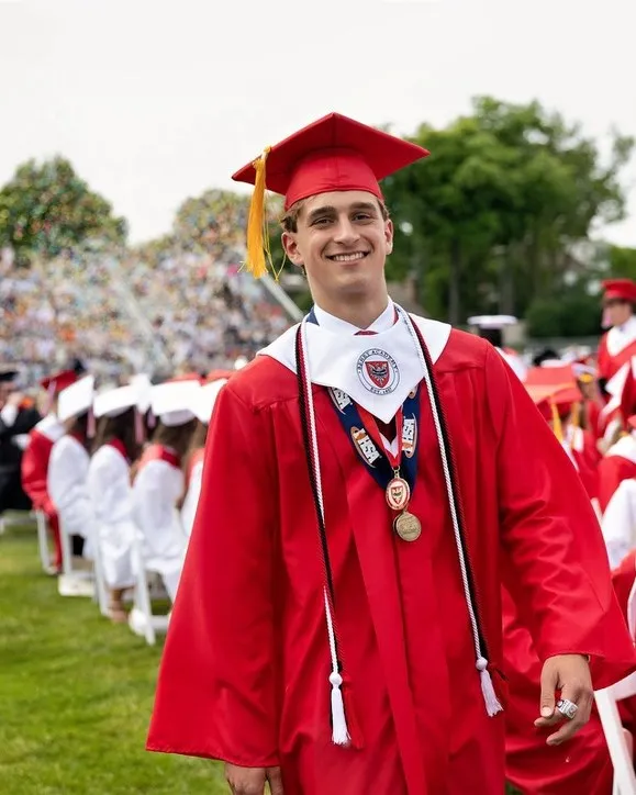 Maclane Zich smiling in a red cap and gown at Benet Academy graduation